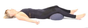 Savasana yoga pose with bolster under knees